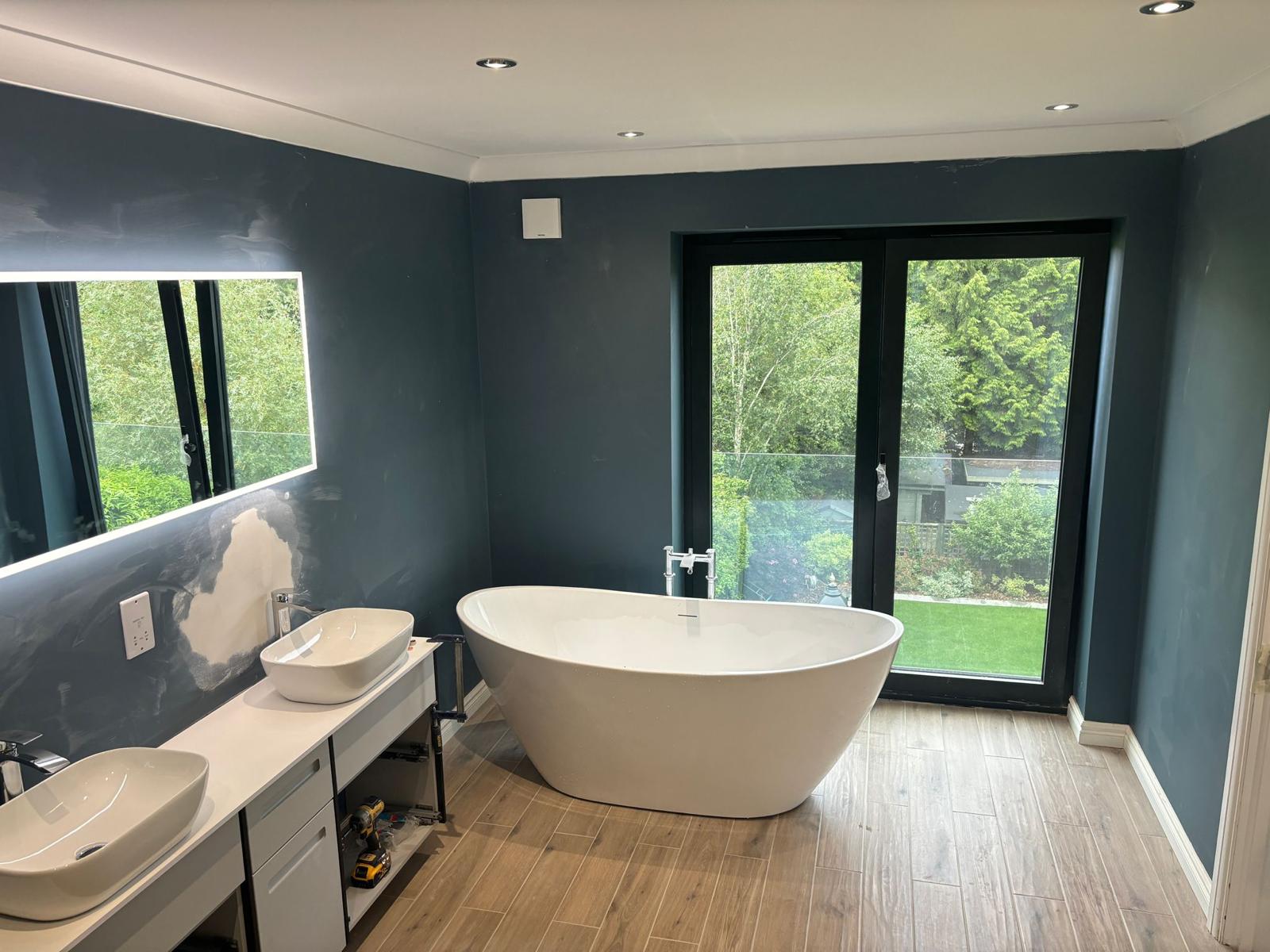 Deep blue bathroom with freestanding tub and garden view