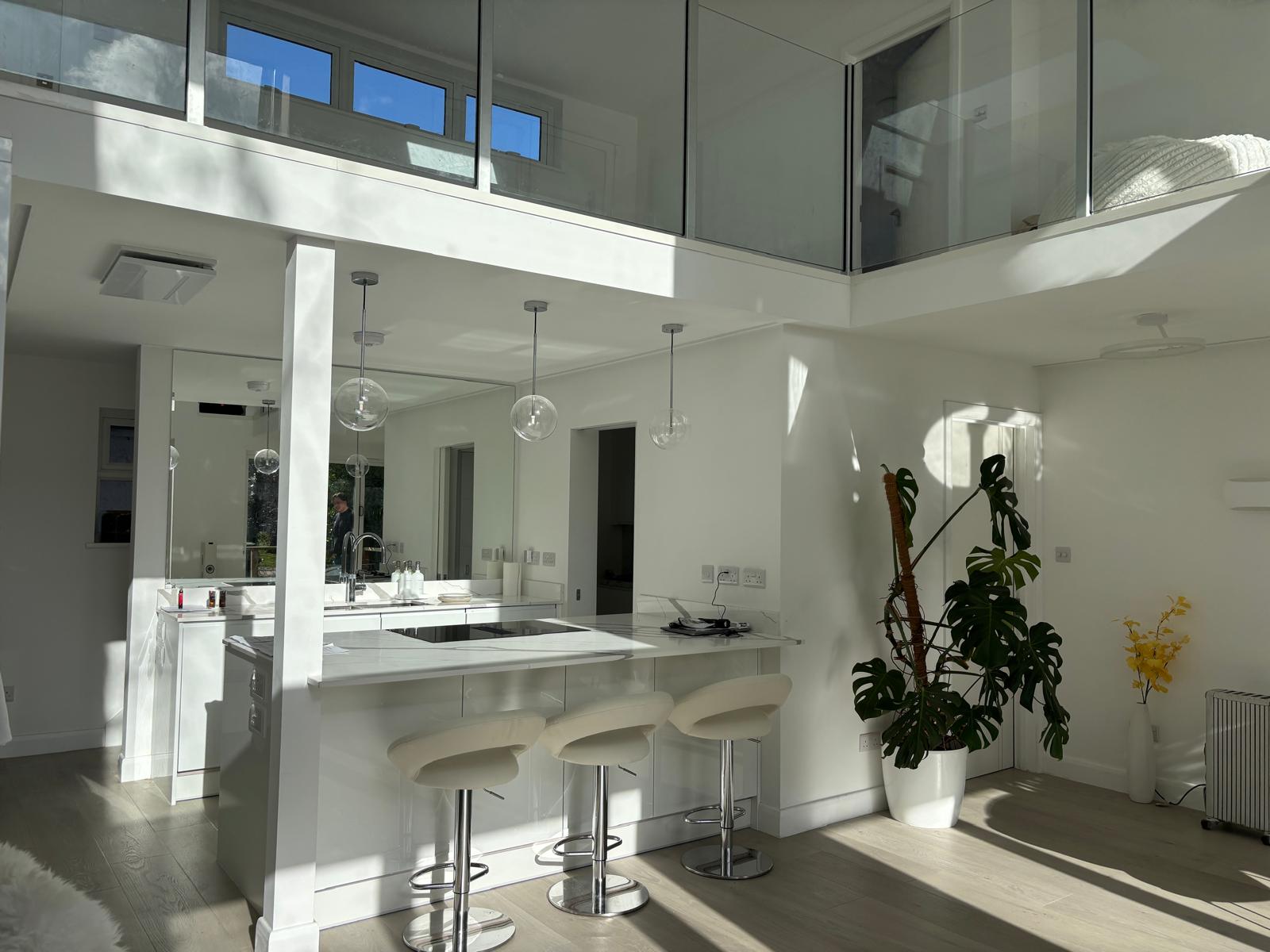 Bright white double-height kitchen with glass mezzanine